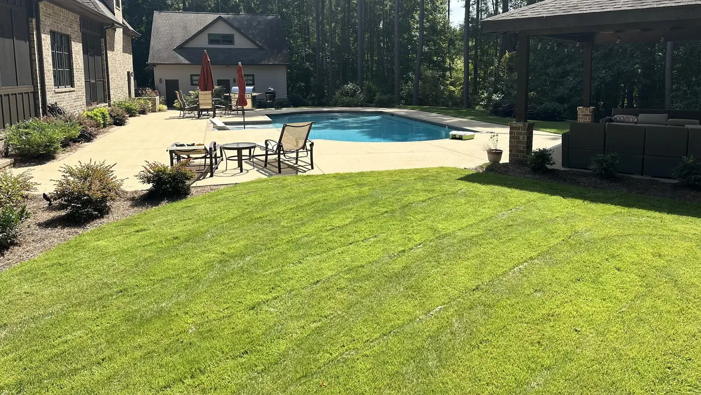 Maintained residential lawn beside a pool and landscaped patio